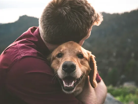 Cuidador abrazando a un golden retriever feliz
